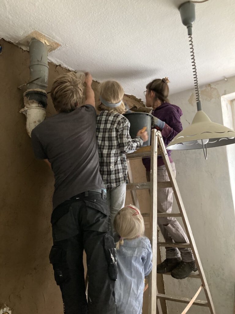 Menschen stehen auf einer Leiter und renovieren ein Zimmer