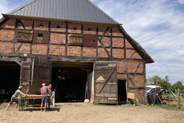 Vor einer alten Scheune wird mit Holz gebaut