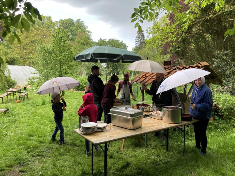 Menschen mit Regenschirmen beim Pizzalehmofen