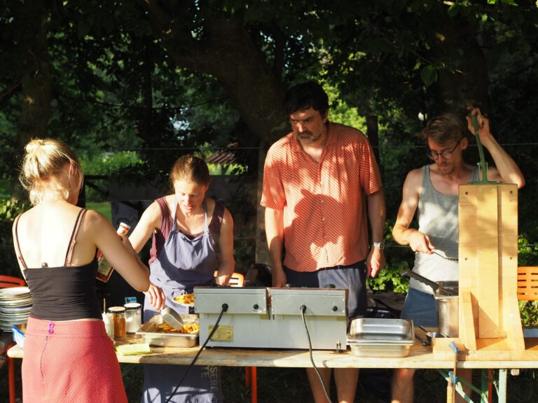 Menschen stehen hinter einem Tisch und machen Pommes